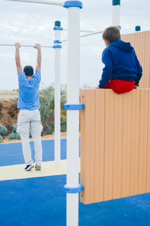 Outdoors fitness training active lifestyle, back view of man doing sport exercising on horizontal...