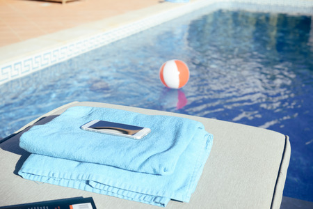 Mobile phone by the pool on sunny background. Modern holiday luxury recreation lifestyleの写真素材