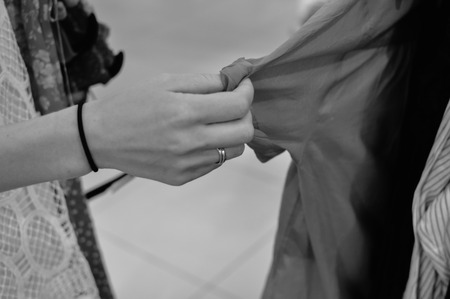 Closeup on hands of a woman holding choosing clothes on shopping background. Modern consumerism lifestyleの写真素材