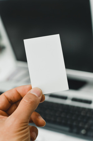 Closeup image of holding business card, person hand showing plain mock up space on professional office background.の写真素材