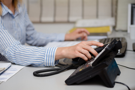 Closeup on busy office phone workplace, light table window. Modern administration control lcd display support solution response. Digital connection device communication landline equipment technologyの写真素材