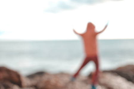Back view of defocused silhouette, unrecognisable person on seaside coastal beauty natural background. Active human and freedom adventure lifestyle, nature scenic walk, relaxing sunlight glowの写真素材