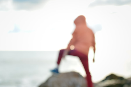 Back view of defocused silhouette, unrecognisable person on seaside coastal beauty natural background. Active human and freedom adventure lifestyle, nature scenic walk, relaxing sunlight glowの写真素材