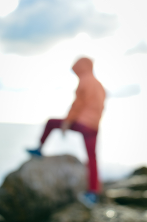 Back view of defocused silhouette, unrecognisable person on seaside coastal beauty natural background. Active human and freedom adventure lifestyle, nature scenic walk, relaxing sunlight glowの写真素材