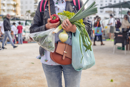 Close up on person buyer hold groceries in bags. Buy sell vegetables. Healthy wellbeing lifestyle backgroundの写真素材
