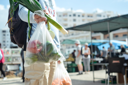 Close up on person buyer hold groceries in bags. Buy sell vegetables. Healthy wellbeing lifestyle backgroundの写真素材