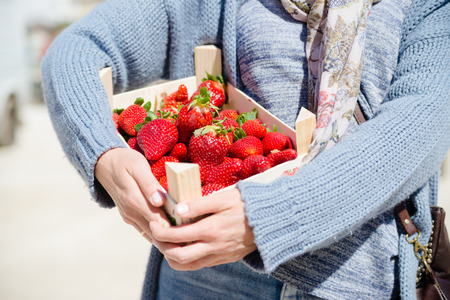 Woman holding bag with strawberries healthy nutritious food on groceries shopping market background, closeup top side view imageの写真素材
