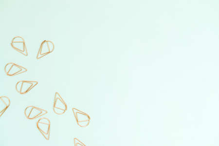 several copper color office paperclips on light blue backgroundの写真素材