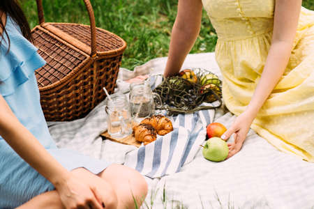 Picnicoutside on the grass with tablecloth, basket, croissants and apples. Summer conceptの写真素材