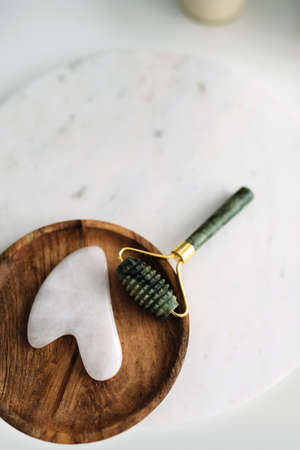 jade facial roller and gua sha tool in wooden tray. Spa concept