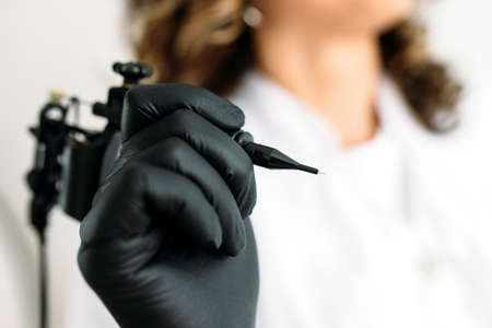woman cosmetologist holding special device for eyebrow tattoo closeup