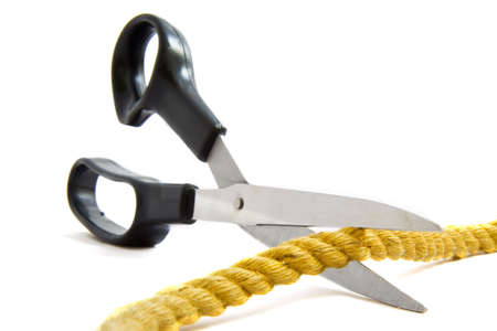 A pair of scissors cutting a rope isolatedの写真素材