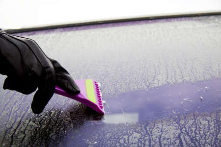 Cleaning the car window with a ice scraper