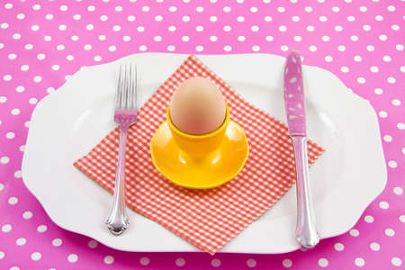 Plate with egg napkin knife and fork on a pink speckles backgroundの写真素材