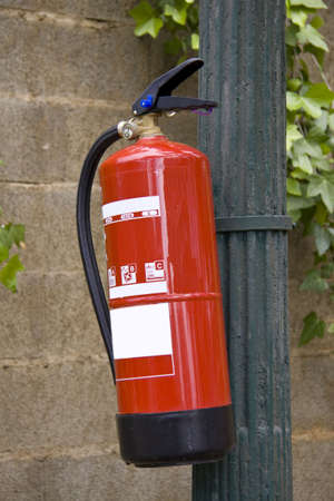 Fire extinguisher fixed on a pole in a nature surrounding