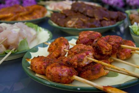 Shrimp kebabs on a plate with meat on the backgroundの写真素材