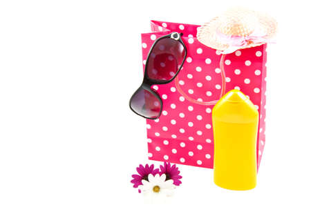 Spotted gift bag with bodylotion hat sun glasses and flowers in front isolated over whiteの写真素材