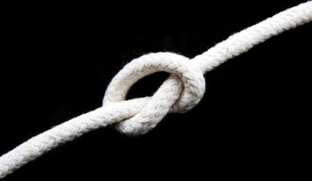 Knot in a white rope isolated over blackの写真素材