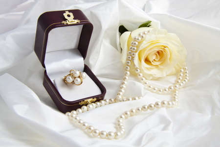 Golden ring with pearls and rose in a gift box on a satin backgroundの写真素材
