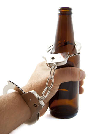 Hand with handcuffs and bottle of beer