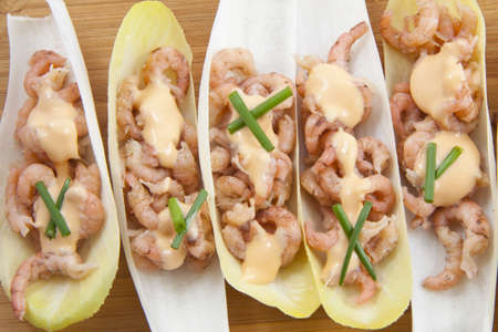 Chicory with shrimp on a wooden plate