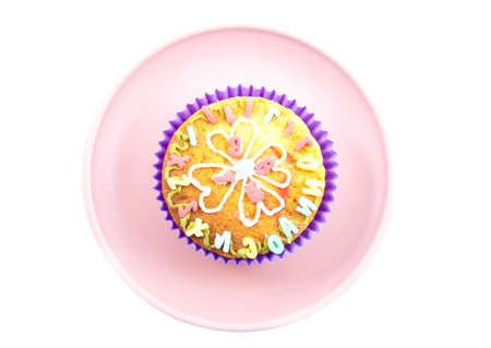 Colorful decorated cupcake on an pink plate isolated over whiteの写真素材