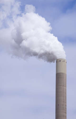 Big large chimney with a lot of smoke in front of a cloudy sky