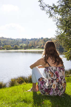 Young girl sitting and watching the lakeの写真素材