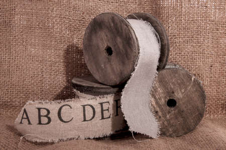 Old vintage ribbon spools on jute backgroundの写真素材