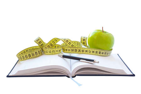 Green apple and centimeter lie on a notepadの写真素材