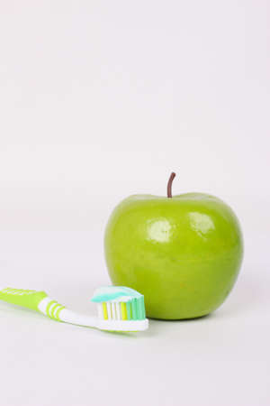 toothbrush with toothpaste and a green apple on a white backgroundの写真素材