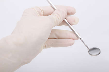 dental mirror in hand on white backgroundの写真素材