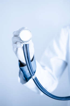 Doctor with a stethoscope in the hands on grey backgroundの写真素材