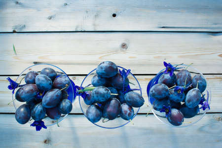The concept of the collection of plum in bowls. Autumn harvest of plum in bowls on a wooden tableの写真素材