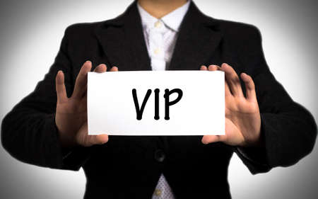 Businesswoman in a black jacket and a white shirt shows a card with the inscription vip. Girl on a white background. Selective focus.の写真素材