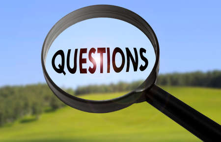Magnifying glass with the word questions on blurred nature background. Searching questions conceptの写真素材