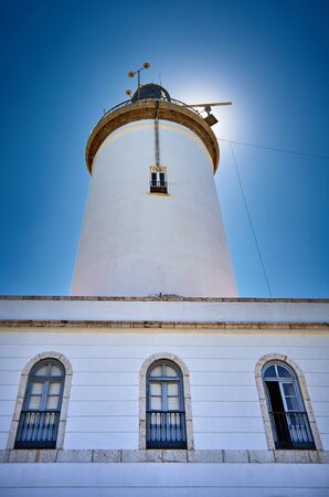 Sun hiding behind a white lighthouse near to the beach of Malaga. Andalusia. Spain.の写真素材