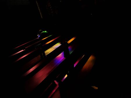 Man praying seated in the banks inside the church of San Francisco, Ãvora, Portugal, illuminated by the colors of the sun through a window.の写真素材