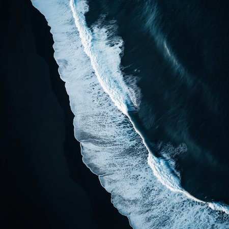 Stunning aerial perspective of ocean waves with white foam crashing on the black sand beach, showcasing the raw beauty of Icelandic natureの写真素材