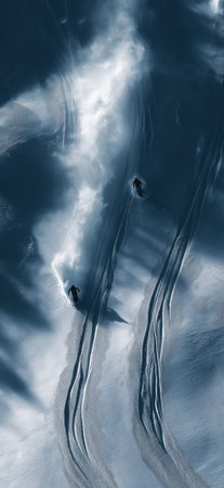 Freeride skiers carving down snowy mountain slope creating powder clouds. Freeride skiingの写真素材
