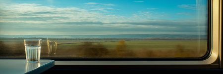 Enjoying a beverage while traveling through scenic countryside seen from a train window. Train journey, autumn landscape rollingの写真素材