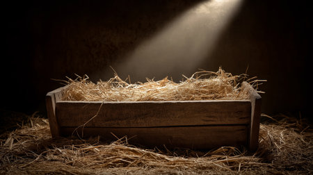 Empty wooden manger with straw receiving warm light, symbolizing birth and new beginnings. Wooden...