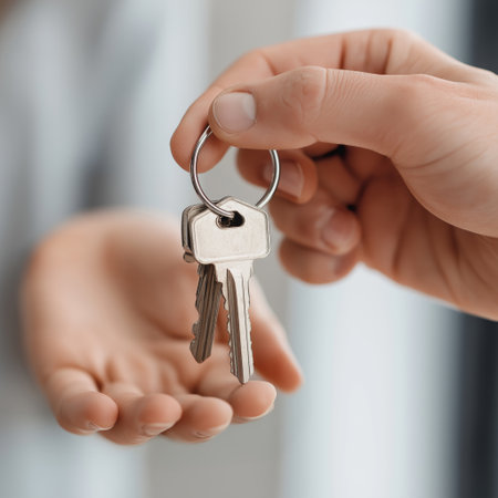 Person's hand passing house keys to another hand during a real estate transaction. Handing over...
