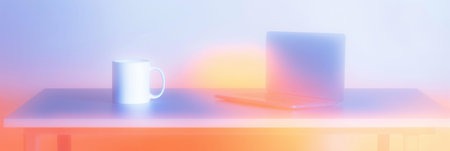Blurry mug and laptop on desk with bright gradients representing work from home. Blurry desk with...