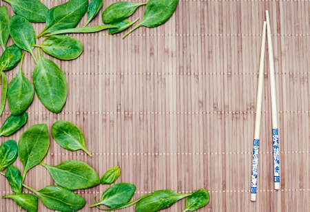 green spinach leaves on a bamboo mat and bamboo chopsticksの写真素材