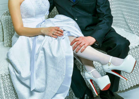 Groom holds bride's leg in white stockingの写真素材