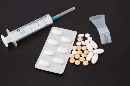 Syringe and tablets for inhalation agent on a black background