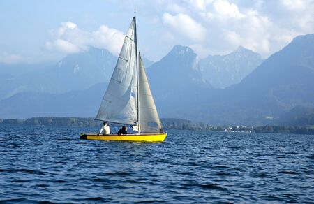 Yellow sailboat sailing on mountains lake. Wolfgangsee, Salzkammergut, Austriaの写真素材