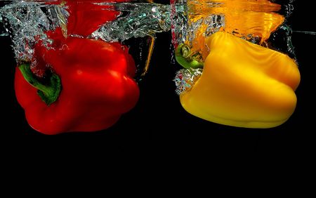 Yellow and red peppers falling into waterの写真素材
