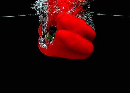 Red pepper falling into waterの写真素材